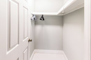 Eine Raumecke mit einer weißen Tür, einer weißen Wand und einem weißen Regal mit zwei hängenden Gegenständen.