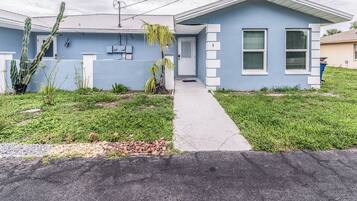 A residential house with a blue exterior, a concrete driveway, and a cactus in the front yard.