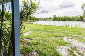 A view of a grassy area with a body of water and trees in the background. - Lakeside Oasis Fort Myers (Fort Myers)