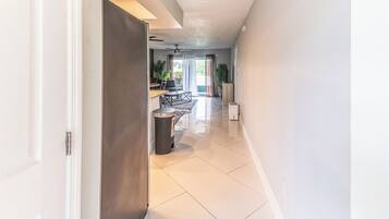 A modern interior with a kitchen, dining area, and a hallway leading to a living space.