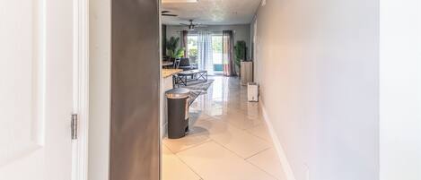 Um interior moderno com cozinha, sala de jantar e corredor que dá acesso a uma sala de estar.