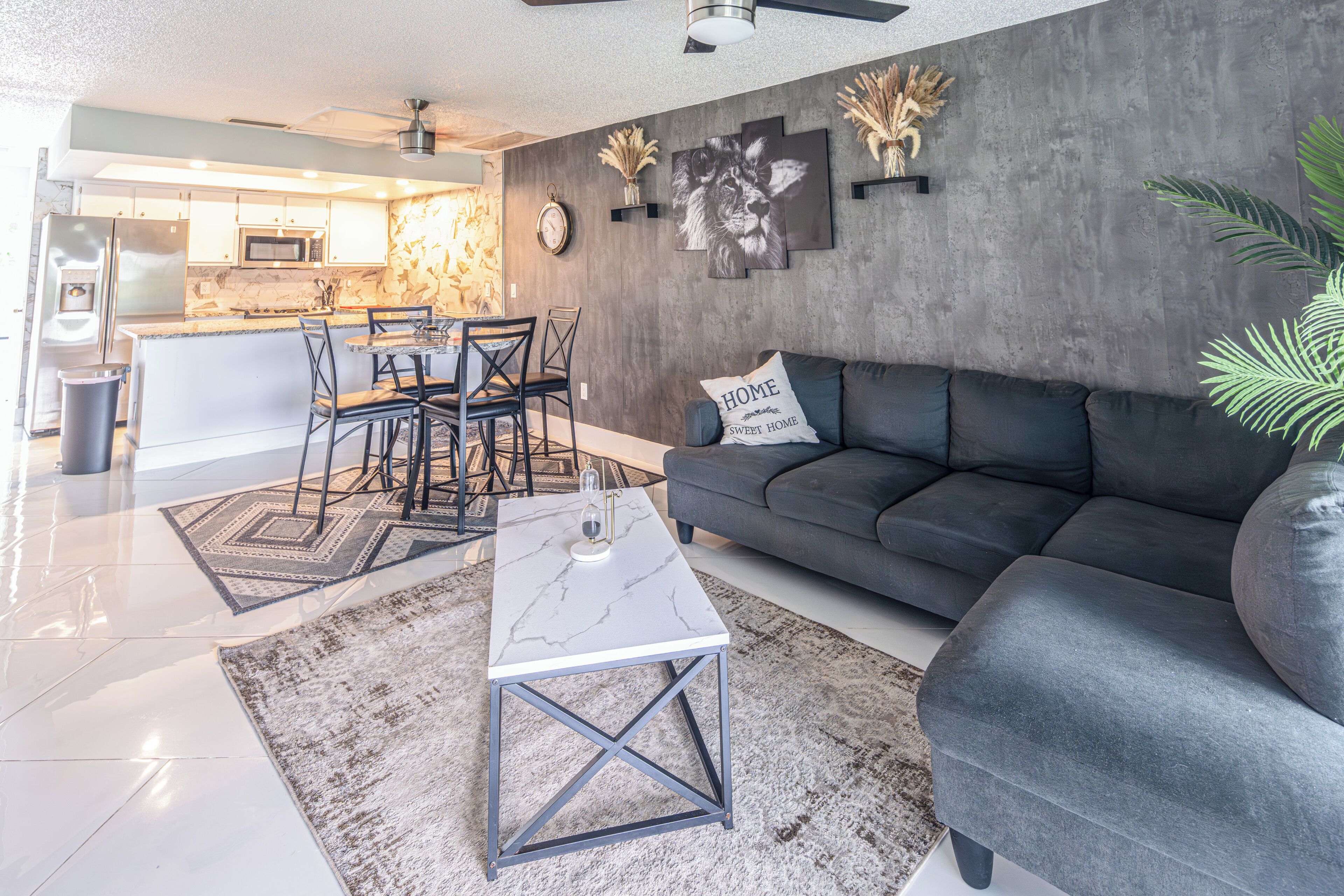 Un salon moderne avec un canapé gris, une table basse et un coin repas comprenant des chaises et une table.
