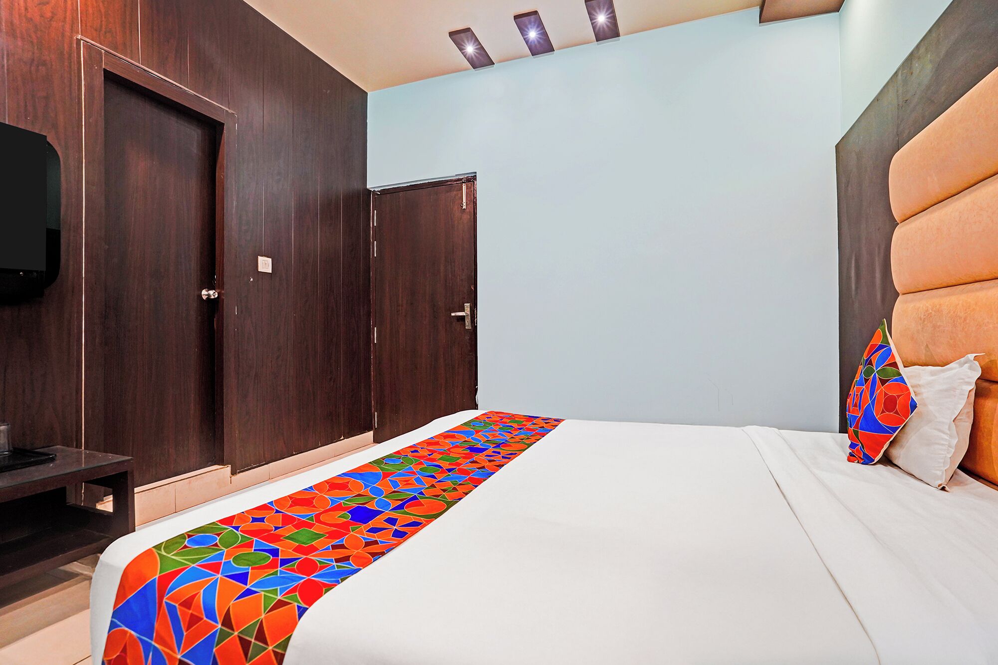 Et hotelværelse med seng, garderobe og fjernsyn.