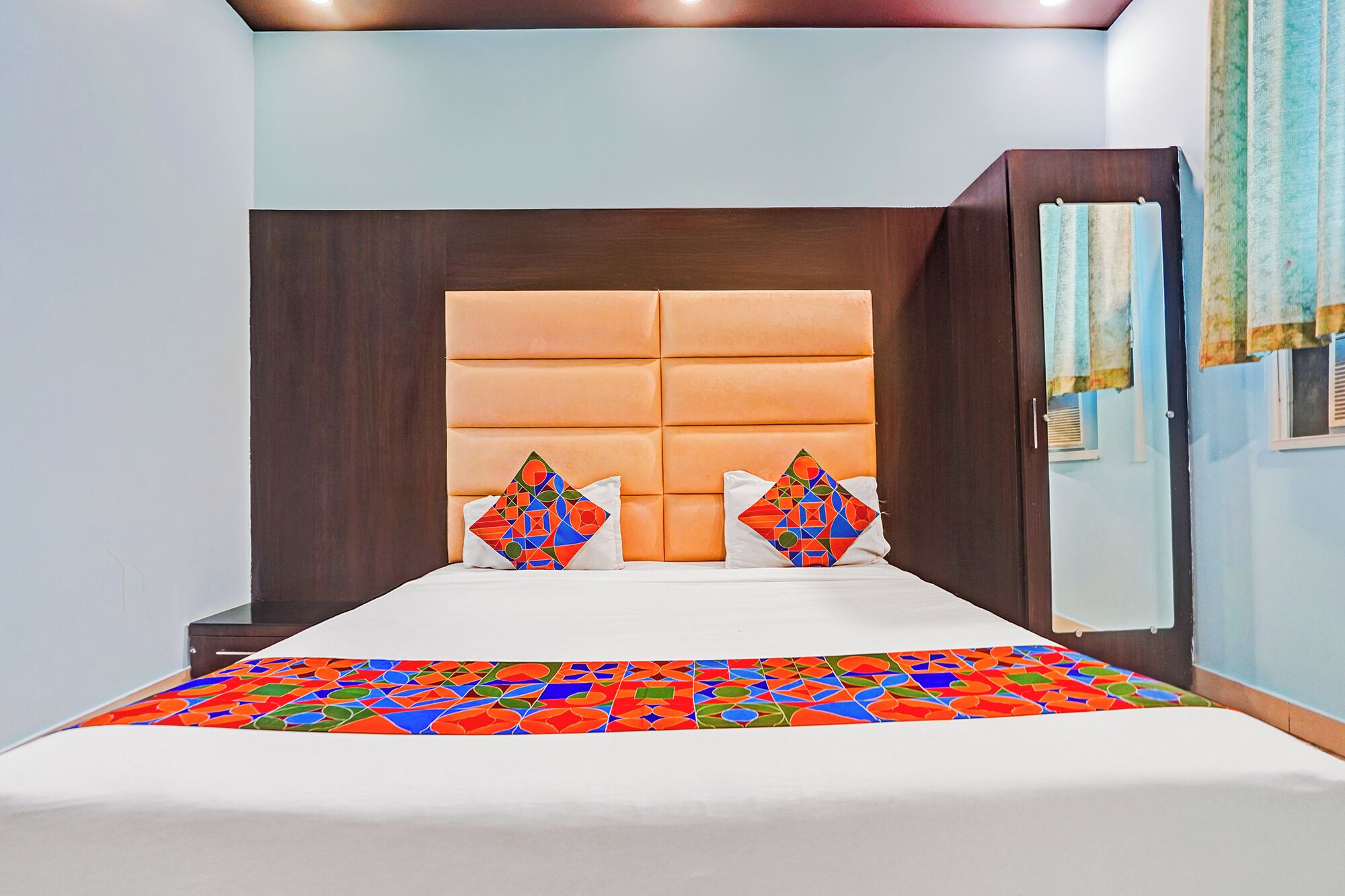 Un dormitorio con una cama grande, cabecera acolchada y dos almohadones decorativos.