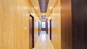 Ein Hotelkorridor mit Holzwänden, Fliesenboden und einer Decke mit dekorativen Paneelen.