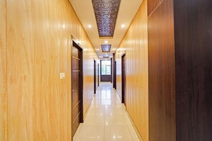 Un pasillo de hotel con paredes de madera, suelo de baldosas y un techo con paneles decorativos.
