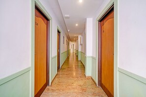 A hotel corridor with wooden doors, green trim, and a marble floor. - Oriva Solmar (Panaji)