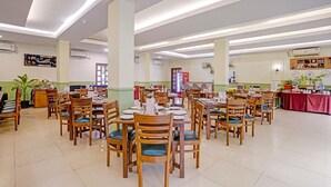 A spacious dining area with multiple tables and chairs, a Coca-Cola refrigerator, and a variety of wall decorations.