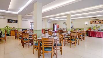 Un comedor amplio con varias mesas y sillas, un refrigerador Coca-Cola y diversas decoraciones en las paredes.