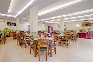 A spacious dining area with multiple tables and chairs, a Coca-Cola refrigerator, and a variety of wall decorations.