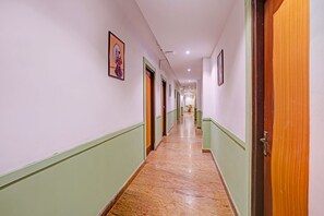 Ein Hotelkorridor mit Türen an beiden Seiten, einem Marmorboden und Bildern in Rahmen an den Wänden.