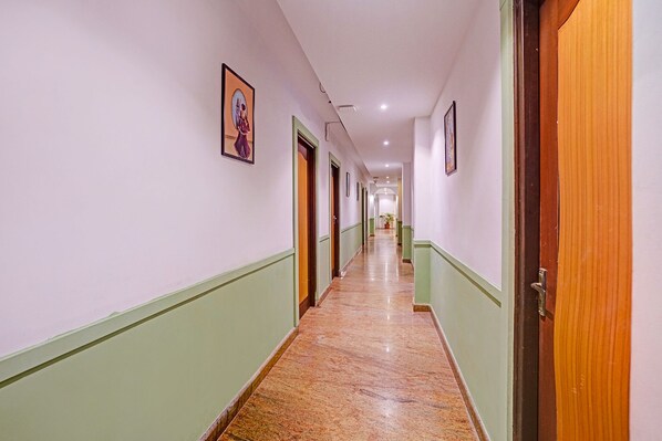 A hotel corridor with doors on both sides, a marble floor, and framed pictures on the walls. - Oriva Solmar (Panaji)