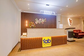 A reception desk with a 'fab hotels' sign, a floral arrangement, and a modern light fixture above. - Oriva Solmar (Panaji)