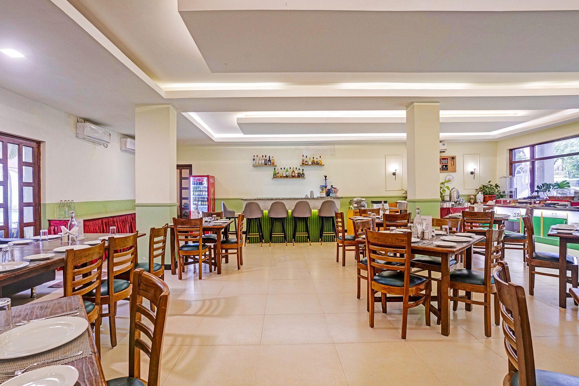 Un restaurante con varias mesas y sillas, una zona de bar y estanterías con botellas.