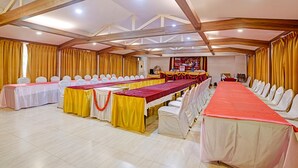 A conference room with multiple tables, white chairs, and yellow curtains.