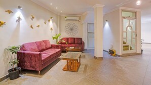 A living room with a red sofa, a wooden coffee table, and a potted plant.