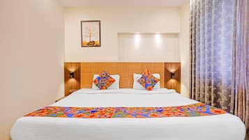 Habitación de hotel con una cama grande, dos lámparas adosadas a la pared, un cuadro enmarcado y una ventana con cortinas.
