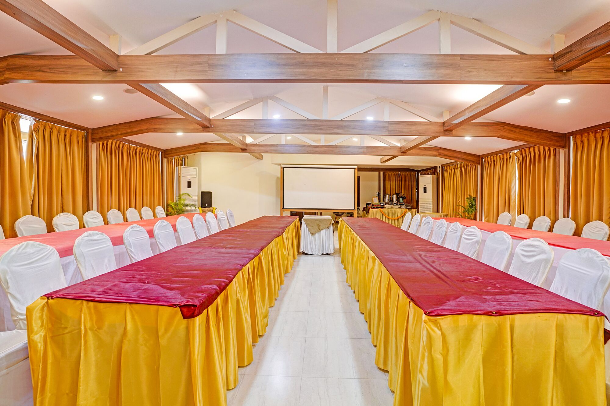A conference room with a long table, white chairs, and yellow curtains.