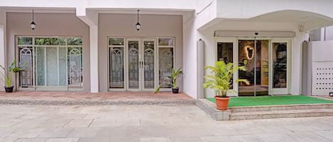 A building with a white facade, double doors with glass panels, and a green carpeted entrance.