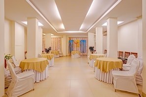 A banquet hall with round tables, white chairs, and a central aisle. - Oriva Solmar (Panaji)