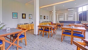 Un comedor de hotel con mesas y sillas, una barra libre y obras de arte en las paredes.