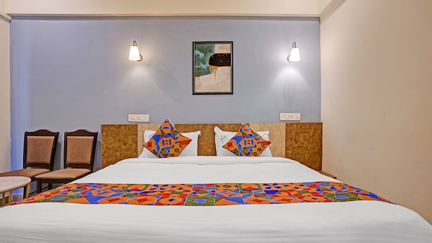Una habitación de hotel con una cama, dos sillas, una mesa y dos luces fijadas en la pared.