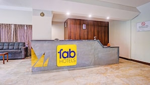 Una recepción con un letrero de 'fab hotels', un panel de pared de madera, un cartel de 'no fumar' y un sofá al fondo.