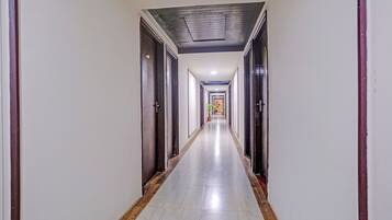 A long, narrow hotel corridor with doors on both sides and a tiled floor.