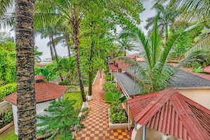 A tropical resort with palm trees, a paved walkway, and red-roofed buildings.