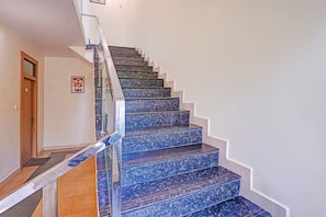 A staircase with a glass railing, leading to a landing.