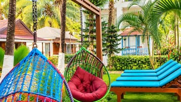 Un resort tropical con una hamaca, una silla roja acolchada y una silla de descanso azul.