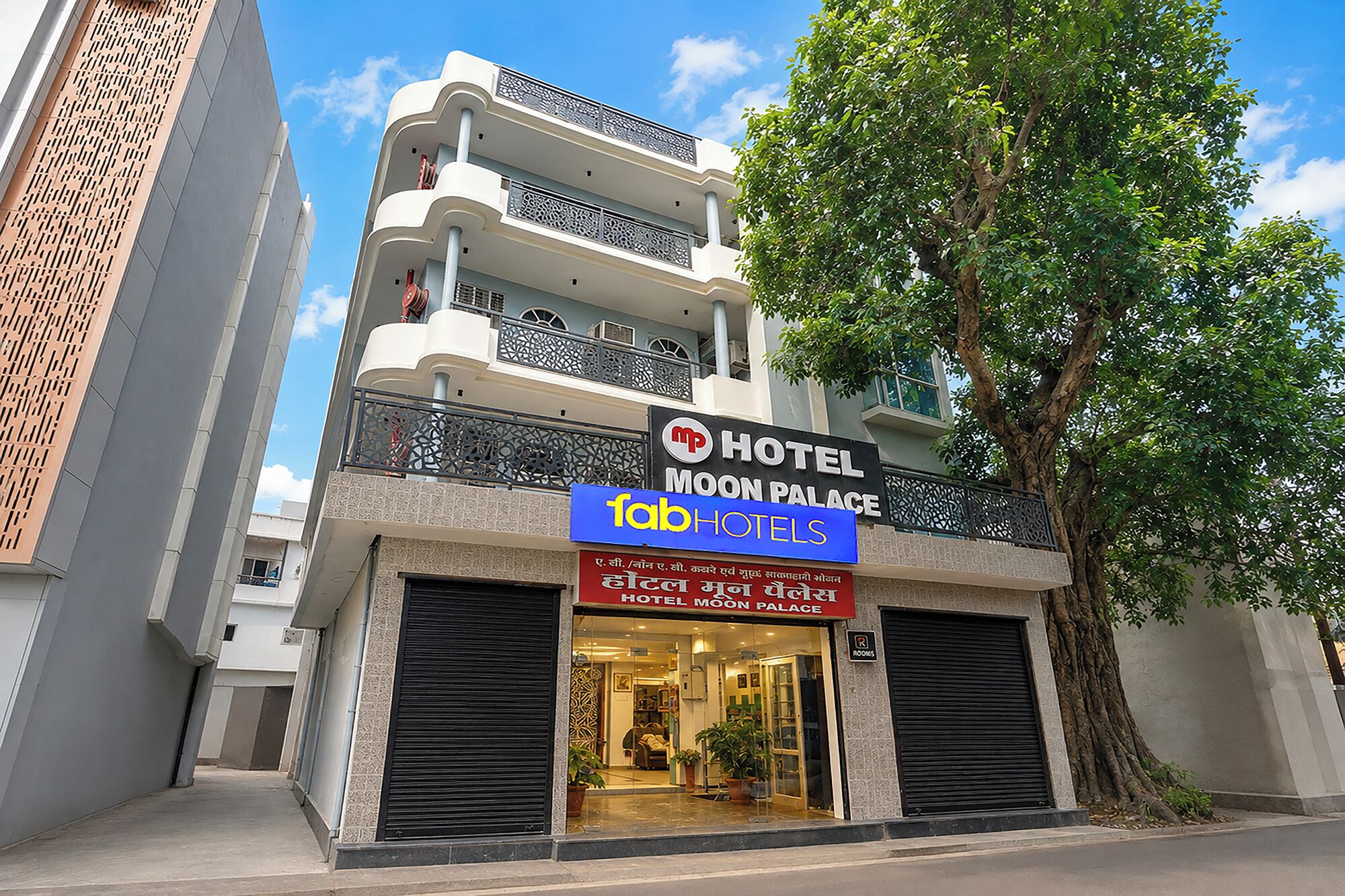A hotel named 'Moon Palace' with a signboard, a tree in front, and a closed entrance.
