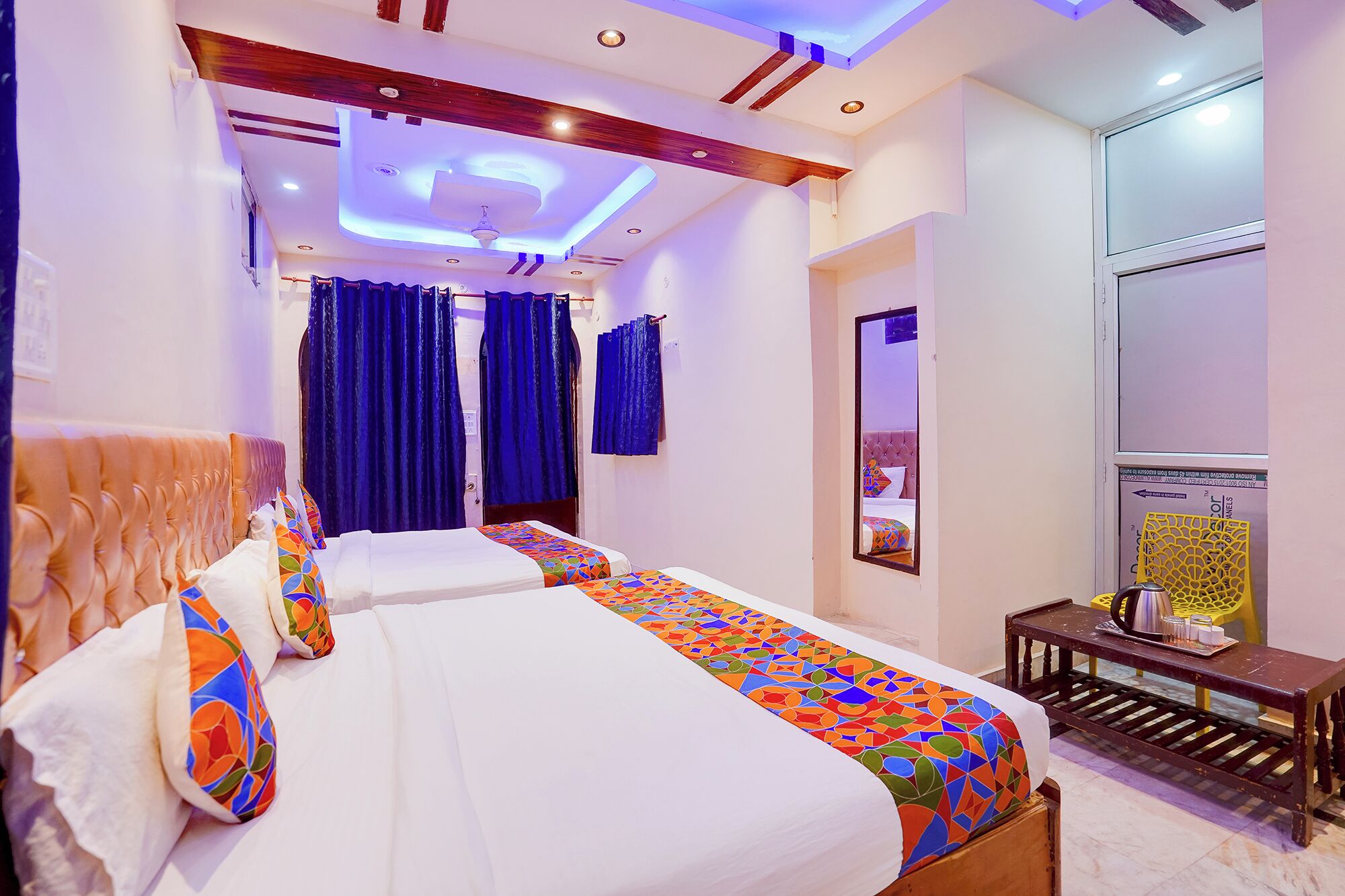 Habitación de hotel de diseño moderno, con una cama grande y ropa de cama colorida, un techo con iluminación empotrada y un espejo grande en la pared.