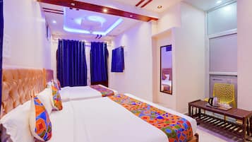 A hotel room with a modern design, featuring a large bed with colorful bedding, a ceiling with recessed lighting, and a large mirror on the wall.