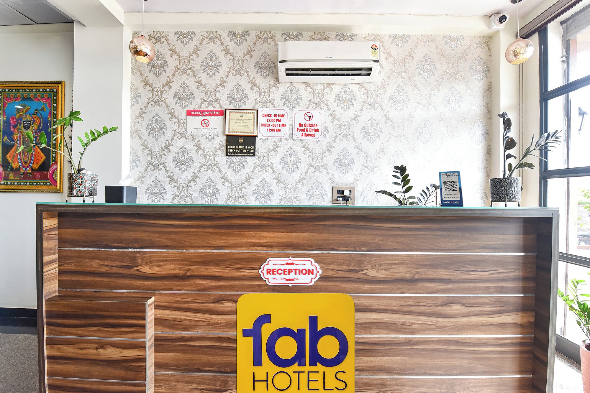 Un mostrador de recepción con detalles de madera, un letrero de recepción y una unidad de aire acondicionado instalada en la pared.