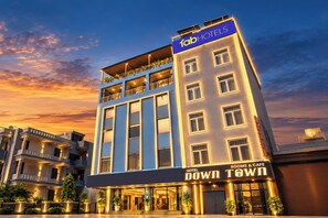 A hotel with a modern facade, multiple balconies, and a sign indicating it offers rooms and a cafe. - Fabhotel Down Town (Jaipur)