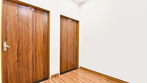 Two wooden doors with numbers 302 and 303, a white wall, and a wooden floor. - Fabhotel Down Town (Jaipur)
