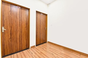 Two wooden doors with numbers 302 and 303, a white wall, and a wooden floor.