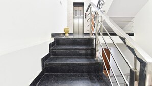 A staircase with a handrail leading to an elevator. - Fabhotel Down Town (Jaipur)