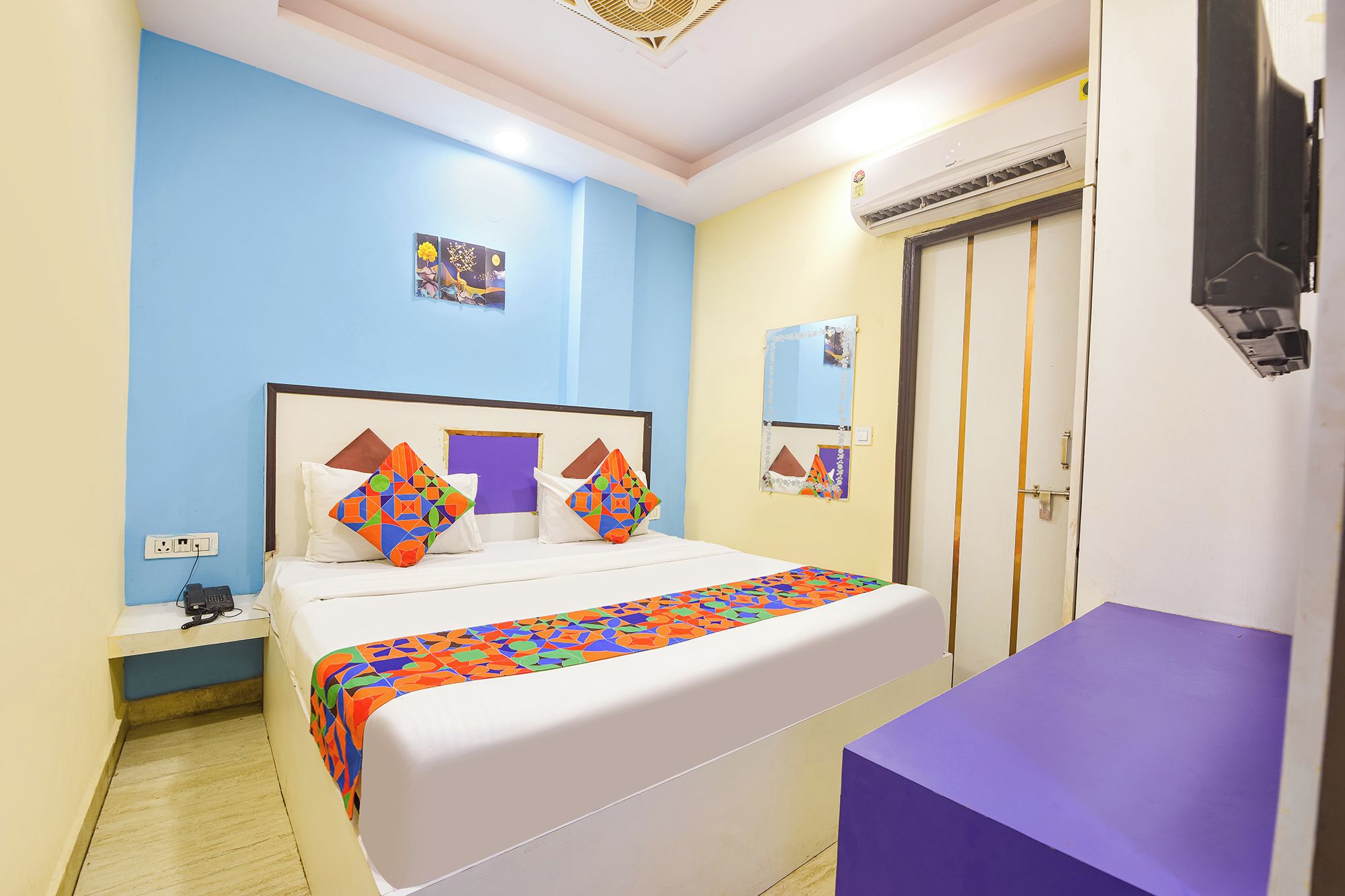 Ein Hotelzimmer mit einem Bett, einem Nachttisch und einer violetten Bank.