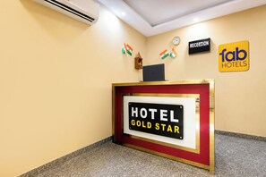 Un taulell de recepció amb un cartell que diu 'HOTEL GOLD STAR' i un rètol de 'RECEPCIÓ' a dalt.