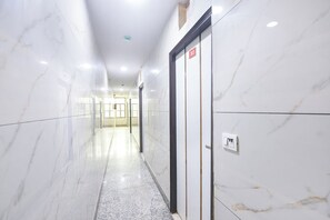 Passadís amb parets i terra de marbre, que condueix a un ascensor amb un indicador del número de planta.