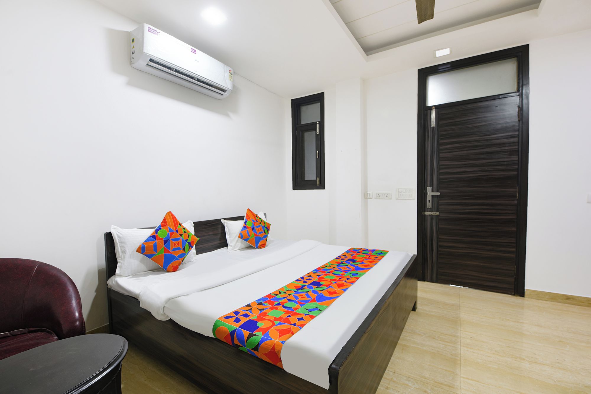Habitación de hotel con cama, una silla, una puerta y un equipo de aire acondicionado.