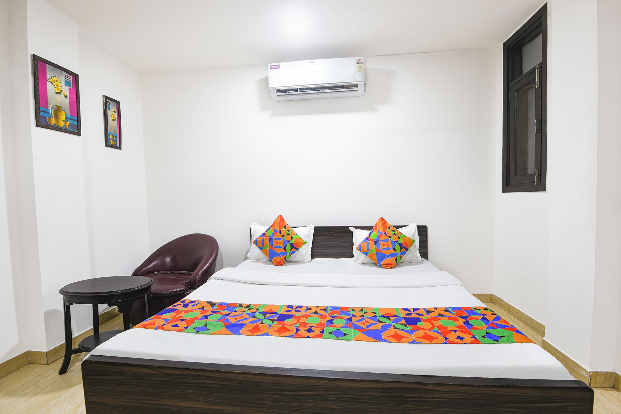 Quarto de hotel com cama, cadeira, ar condicionado e janela.