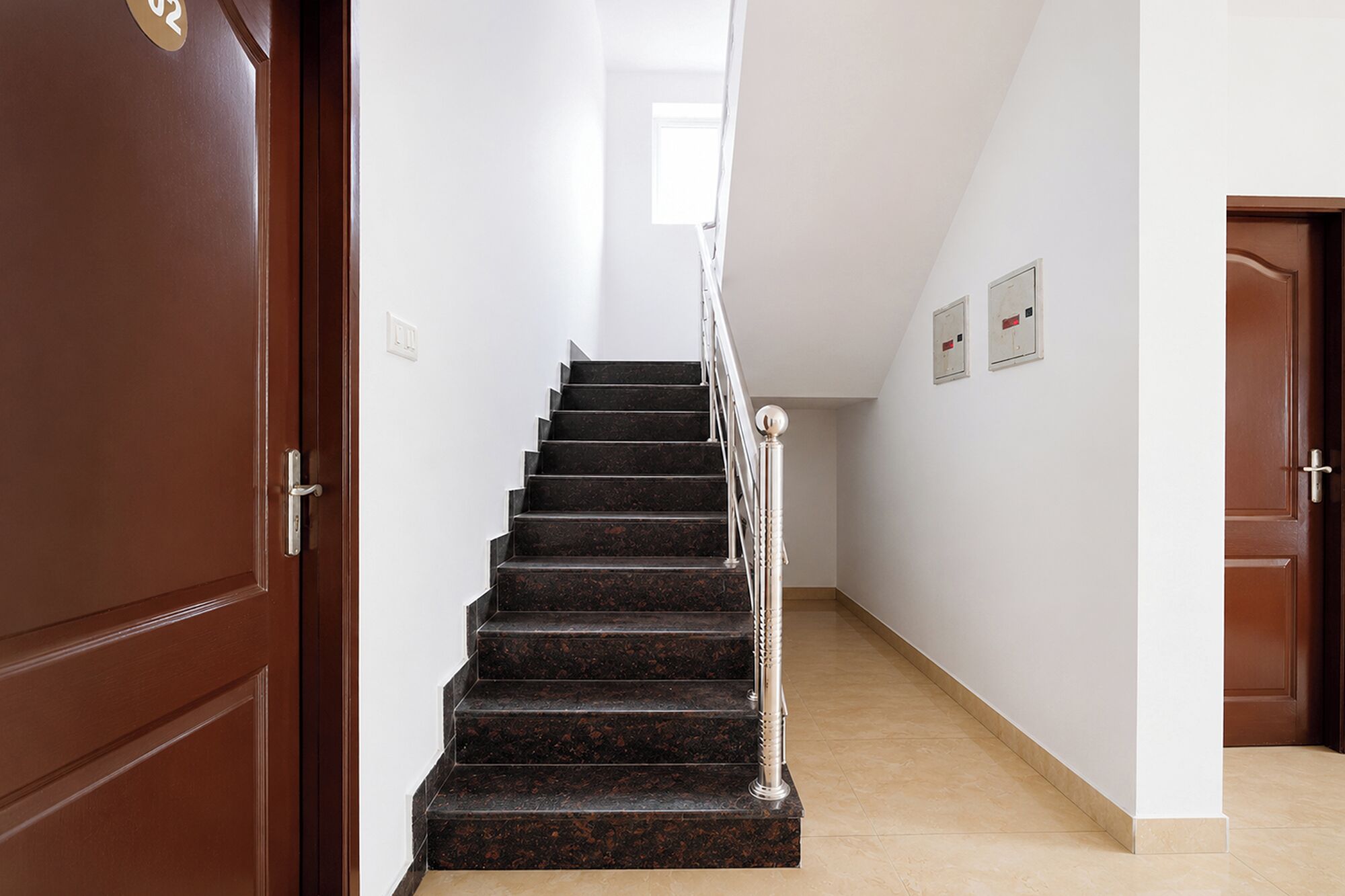 Una escala amb barana metàl·lica i una porta de fusta a l'esquerra.