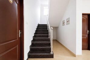Un escalier avec une rampe métallique et une porte en bois sur le côté gauche.