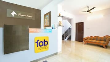 A hotel reception area with a sign for 'Tab Hotels', a staircase, and a sofa.