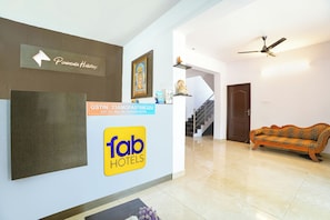 A hotel reception area with a sign for 'Tab Hotels', a staircase, and a sofa.