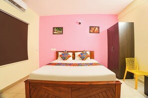 A bedroom with a bed, a wardrobe, a chair, and two wall-mounted pictures.