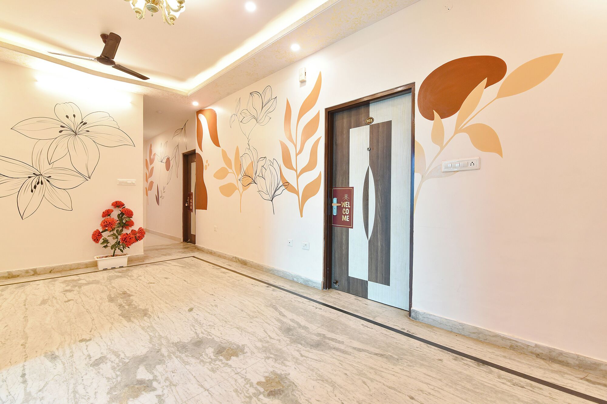 Un vestíbulo de hotel con diseño moderno, que cuenta con un mostrador de recepción, una pared con arte floral y un cartel de bienvenida.